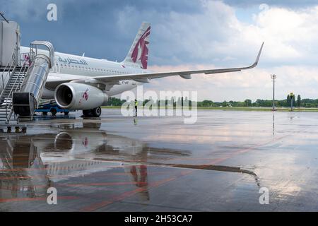 UKRAINE, KIEW, - 28. MAI 2021: Regnerisches Wetter. Passagiere, die einsteigen, Gepäck beladen. Flugzeug von Qatar Airlines auf der Start- und Landebahn des Flughafens Boryspil. Airbus A320-232, Flugzeug - A7-AHR. Regen über die Pfützen. Stockfoto