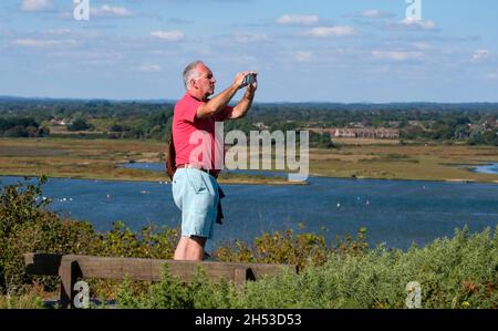 Mann, der an einem sonnigen Tag in Dorset eine Aufnahme eines Blickes von Hengistbury Head fotografiert Stockfoto