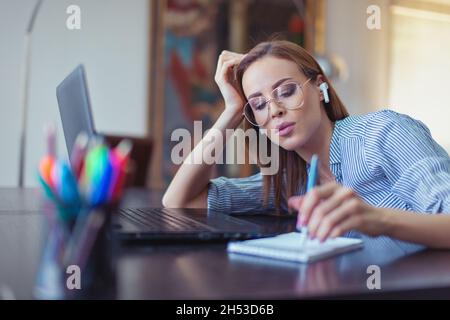 Nerd kaukasischen universitären Studenten mit Freisprecheinrichtung Notizen am Laptop Stockfoto