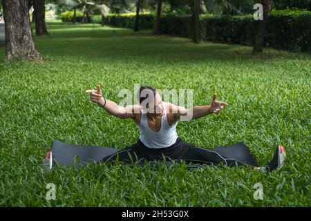 Sportlich aktiver junger Mann in Sportbekleidung, der im Park Sportübungen macht. Porträt eines gutaussehenden fitchen Mannes, der Stretching-Übungen im Freien macht. Stockfoto