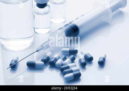 Spritzenpillen und einige Fläschchen auf weißem Hintergrund. Duotone-Bild. Stockfoto