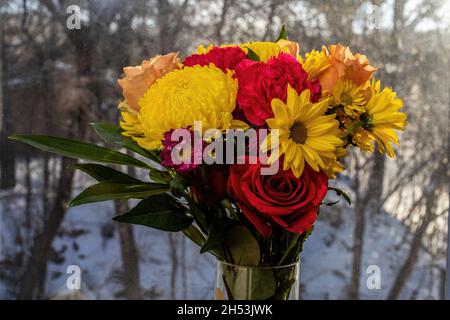 Wunderschöne Blumenarrangements in Rot und Gelb vor schneebedecktem Hintergrund. Stockfoto