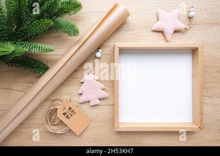 Leere Geschenkbox mit Kopierplatz, Rolle Kraftpapier, Weihnachtsschmuck und Tannenzweig auf Holzhintergrund. Eco-Verpackungskonzept, keine Verschwendung Stockfoto
