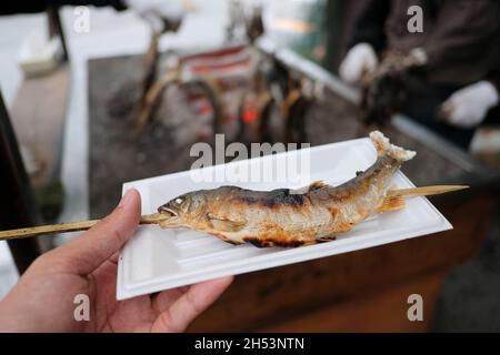 Kohlegrillter Ayu-Fisch mit Salz auf weißem Teller. Traditionelles japanisches Street Food am Kegon Wasserfall in Nikko, Japan. Stockfoto