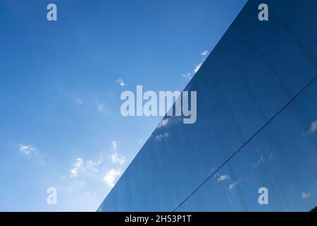 Die Metallfassade des Grand Central Bahnhofs spiegelt am 15. Oktober 2021 in Birmingham, Großbritannien, blauen Himmel und Wolken wider. Grand Central ist ein Einkaufszentrum in Birmingham, England, das am 24. September 2015 eröffnet wurde. Es gehört derzeit Hammerson und CPPIB. Das ursprüngliche Zentrum wurde 1971 als Teil des Wiederaufbaus des Bahnhofs Birmingham New Street erbaut. Es war bekannt als Birmingham Shopping Centre, bevor es in Pallasades umbenannt wurde. Im Rahmen der Neuentwicklung des New Street Station Gateway Plus wurde das Grand Central grundlegend überarbeitet. Stockfoto