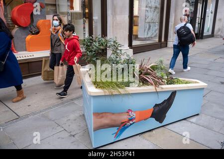 Die Werbung für die Stiefel von Dr. Martens interagiert mit vorbeifahrenden Fußgängern auf der Regent Street, dem Einkaufsviertel, das in den letzten 18 Monaten voller ist als je zu irgendeinem Zeitpunkt, da die Käufer ins West End kommen und das Einzelhandelsgeschäft am 19. Oktober 2021 in London, Großbritannien, wieder gut anlaufen wird. Viele Menschen tragen Gesichtsmasken an überfüllten Orten wie diesem, aber sie sind nicht mehr obligatorisch, während der Rat der Regierung nahelegt, dass es ratsam ist, eine Gesichtsbedeckung an belebten öffentlichen Plätzen im Inneren und auf dem Transport zu tragen, viele Menschen tragen sie immer noch draußen. Stockfoto