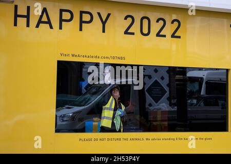 Arbeiter putzt ein Fenster unter einem Schild mit der Aufschrift Happy 2022 auf der Bond Street am 20. Oktober 2021 in London, Großbritannien. Die Bond Street ist eine der Hauptstraßen im Einkaufsviertel West End und sehr nobly. Seit dem 18. Jahrhundert ist es eine modische Einkaufsstraße. Die reichen und wohlhabenden Shop hier vor allem für High-End-Mode und Schmuck. Stockfoto