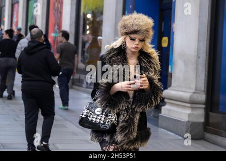 Junge Frau mit voluminösen gefälschten Wimpern und einem wahrhaft einzigartigen Sinn für Stil, die am 20. Oktober 2021 in London, Großbritannien, entlang der Oxford Street spazierengeht. Stockfoto