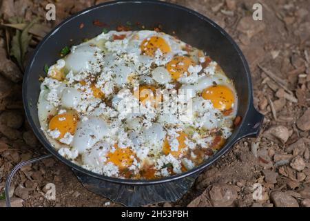 Shakshouka, ein traditionelles Gericht aus pochierten Eiern in Sauce aus Tomaten, Harissa, Olivenöl, Zwiebeln, Knoblauch und Gewürzen, In einer Pfanne im Freien gekocht Stockfoto
