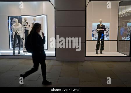 Menschen, die vor den Schaufenstern der Luxusmarke Dior in der Bond Street, London, England, Großbritannien, laufen Stockfoto