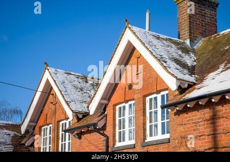 Altes Haus mit schlichten Lehmdachziegeln, Schnee auf dem Dachdach im Winter, Großbritannien. Dachisolierung und Konzepte zur Verbesserung der Wohnqualität. Stockfoto