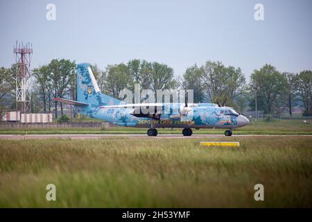 UKRAINE, KIEW, - 28. MAI 2021: AN-26 der ukrainischen Streitkräfte Flugzeug auf der Start- und Landebahn des Flughafens. Flugzeuganflug. Abends dunkle Sturmwolken. Dramatischer Himmel. Vorfeld und Terminal des Flughafens. Stockfoto