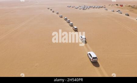 Geländewagen mit Geländewagen, die durch die Sanddünen in der Wüste von Abu Dhabi fahren. Lager. Blick von oben auf SUVs in der Wüste. Stockfoto