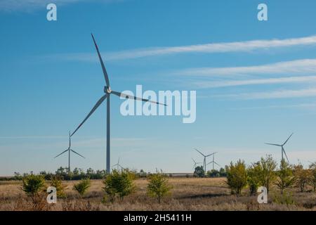 Windturbinen im offenen Gelände an windigen Tagen mit dunklen Wolken am Himmel. Alternative Stromerzeugung. Stockfoto