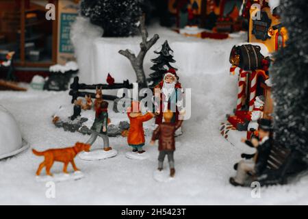 Weihnachtsfiguren von Weihnachtsmann und Kindern, die in der verschneiten Straße spielen. Berühmte Lemax Spielzeug, Weihnachten Winter Geschenke und Dekorationen. Stockfoto