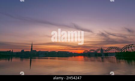 Der Sonnenaufgang über dem alten Riga spiegelte sich im Spiegel der Daugava wider Stockfoto