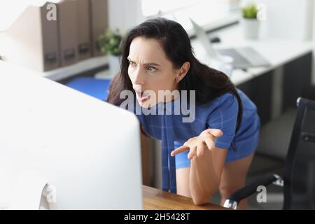 Überraschte Geschäftsfrau, die im Büro auf den Computerbildschirm schaute Stockfoto