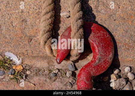 Ein roter Metallhaken und -Seil zur Sicherung - Charlestown, Cornwall, Großbritannien Stockfoto