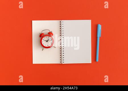 Roter Wecker und Notizbücher mit Platz für Text auf rotem Hintergrund Stockfoto