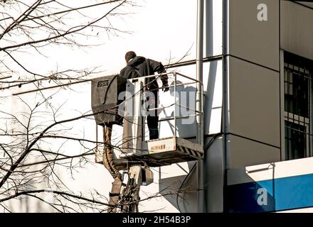 Dnepropetrovsk, Ukraine - 10.22. 2021: Ein Bauherr führt Hochhaus-Fassadenarbeiten an einem Hubkorb durch. Stockfoto