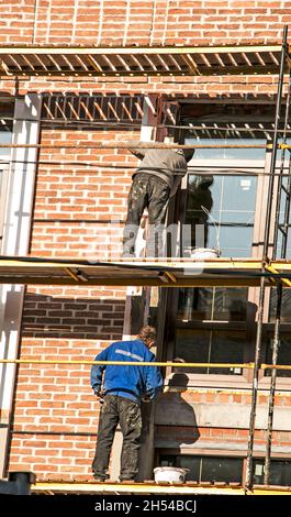 Die Bauherren führen die Fertigstellung der Fassade auf dem Gerüst durch Stockfoto