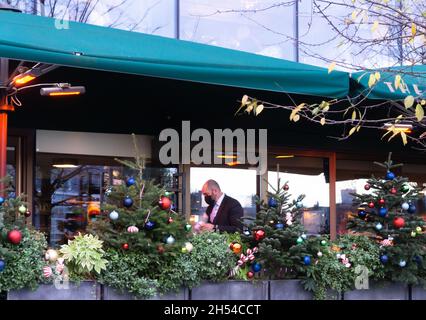 London, Großbritannien, 06. Dezember 2020. Weihnachtsbaumkugelschmuck mit einem Kellner, der eine Maske trägt und im Restaurant Essen serviert. Covid-19, 2020. Stockfoto