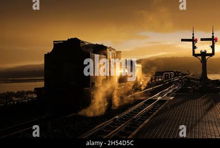 Die Sonne geht gerade über den Hügeln auf, als der Regen gerade anfängt und Garratt 130 am 3.11.21 in Porthmadog pausiert Stockfoto