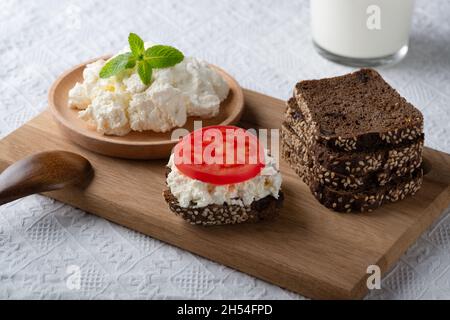 Roggenbrotscheiben mit Quark und Tomate auf Holzplatte Stockfoto