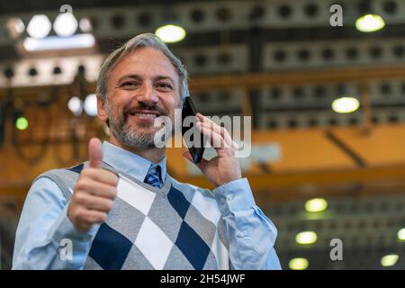 Taille Nach Oben Porträt Eines Selbstbewussten, Hübschen, Grauhaarigen Geschäftsmanns Oder Ingenieurs Im Industriellen Innenausbau. Charismatischer Mann Steht Und Benutzt Handy In Stockfoto
