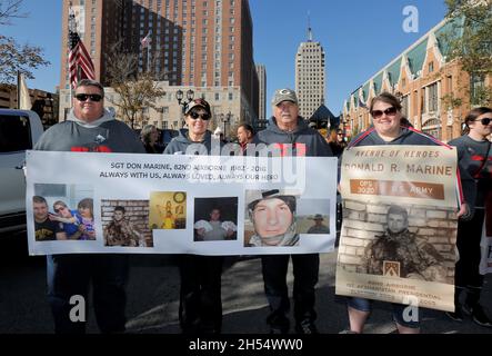 Milwaukee, Wisconsin, USA. November 2021. Die Marine-Familie aus Neillsville, Wisconsin: Bruce Brey (Onkel), Linda Marine (Mutter), Mickey Mazola und Kari Marine (Schwester) halten ein Gedenkbanner der verstorbenen Sgt. Donald R. Marine, der nach seiner 5. Tour in Afghanistan im Einsatz getötet wurde. Nach einem Jahr Pause aufgrund der COVID-Pandemie im Jahr 2020 startete die Veteran's Day Parade, die von der Wisconsin Veterans Chamber of Commerce organisiert wurde, am Samstag, dem 6. November 2021 in der Innenstadt von Milwaukee. Eine Mischung aus Schwimmern, Patriotismus und militärischer Ausrüstung wird von der 5th und Wisconsin Avenue nach Osten Rollen Stockfoto