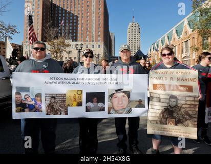 Milwaukee, Wisconsin, USA. November 2021. Die Marine-Familie aus Neillsville, Wisconsin: Bruce Brey (Onkel), Linda Marine (Mutter), Mickey Mazola und Kari Marine (Schwester) halten ein Gedenkbanner der verstorbenen Sgt. Donald R. Marine, der nach seiner 5. Tour in Afghanistan im Einsatz getötet wurde. Nach einem Jahr Pause aufgrund der COVID-Pandemie im Jahr 2020 startete die Veteran's Day Parade, die von der Wisconsin Veterans Chamber of Commerce organisiert wurde, am Samstag, dem 6. November 2021 in der Innenstadt von Milwaukee. Eine Mischung aus Schwimmern, Patriotismus und militärischer Ausrüstung wird von der 5th und Wisconsin Avenue nach Osten Rollen Stockfoto