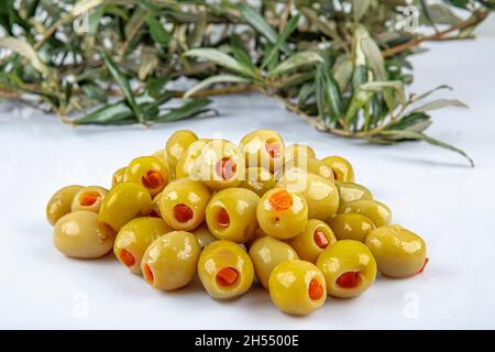 Eingelegte kleine grüne Oliven, gefüllt mit rotem Paprika in einer Holzschüssel. Früchte von Olea europaea, gefüllt mit Paprika-Scheiben. Nahaufnahme von Abov Stockfoto