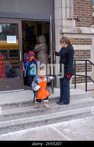 St. Paul, Minnesota. Charterschule für die Hmong. Hmong-Schüler verlassen an einem kalten Tag die Schule, um in den Schulbus zu steigen. Stockfoto