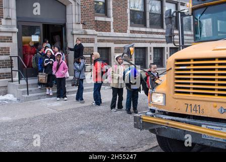 St. Paul, Minnesota. Charterschule für die Hmong. Hmong-Schüler verlassen an einem kalten Tag die Schule, um in den Schulbus zu steigen. Stockfoto