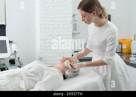 Reife Frau erhält whte Gesichtsmaske im Spa Schönheitssalon. Konzept der Hautpflege für ältere Menschen Stockfoto