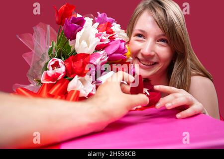 Nahaufnahme Foto einer schönen fröhlichen blonden Dame mit einem Tulpen farbigen Strauß und die Annahme der Heiratsantrag von ihrem Freund, er hält einen Stockfoto
