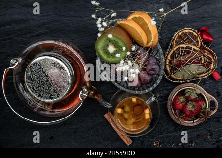 Ein Glas frisch gebrühtes Obst und Kräutertee. Dunklerer Hintergrund. Draufsicht. Stockfoto