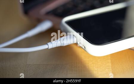 Ein Smartphone wird von einer kleinen weißen Powerbank geladen. Stockfoto