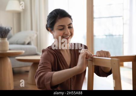 Junge Inderin sammelt allein zu Hause einen neuen Holzstuhl ein Stockfoto