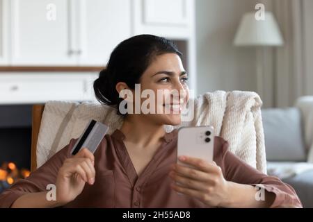 Indische Frau hält Kreditkarte und Smartphone kaufen Waren online Stockfoto