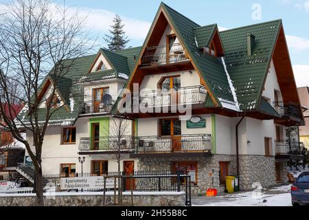 Zakopane, Polen - 21. März 2018: Ein Backsteingebäude mit schrägen Dächern, das grün ist, ist ein Gästehaus unter dem lokalen Namen Willa Karpi Stockfoto