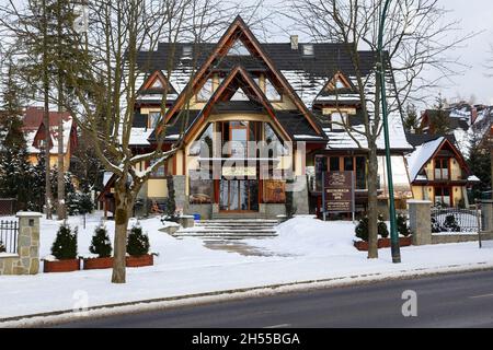 Zakopane, Polen - 21. März 2018: Die Frontfassade mit schrägen Dächern ist ein modernes Hotelgebäude, das mit traditioneller regionaler Architektur gebaut wurde Stockfoto