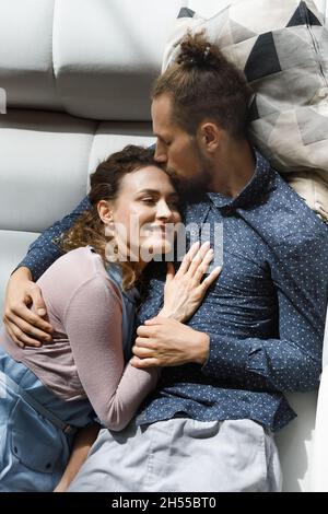 Glücklich liebenden Mann küssen schöne Frau, entspannen auf dem Sofa. Stockfoto