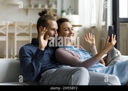 Glückliches junges Familienpaar mit mobilem Videoanruf. Stockfoto