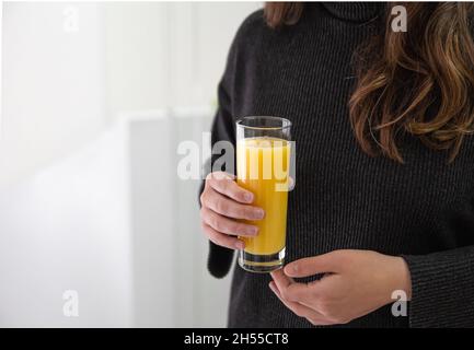 Ein Glas Orangensaft in weiblichen Händen, Nahaufnahme. Stockfoto