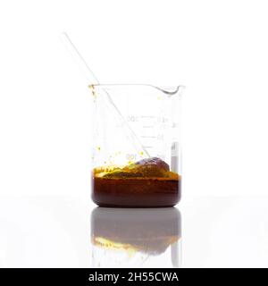 Chemische Zutat aus der Nähe auf weißem Labortisch. Eisenchlorid-Flüssigkeit mit Rührstab im Becher. Seitenansicht Stockfoto