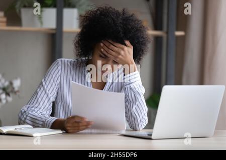 Unglückliche afroamerikanische Frau, die schlechte Nachrichten in einem Brief liest Stockfoto