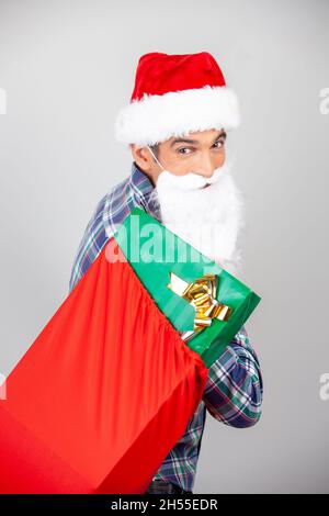 Glücklicher lächelnder Mann mit Weihnachtshut, der rote Geschenkschachteln auf weißem Hintergrund zeigt Stockfoto