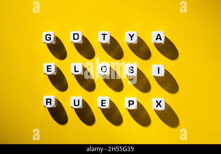 Weiße Würfel mit zufällig auf gelbem Hintergrund verstreuten Buchstaben Stockfoto