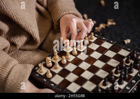 Frau, die Schachfiguren auf ein Schachbrett legt. Stockfoto